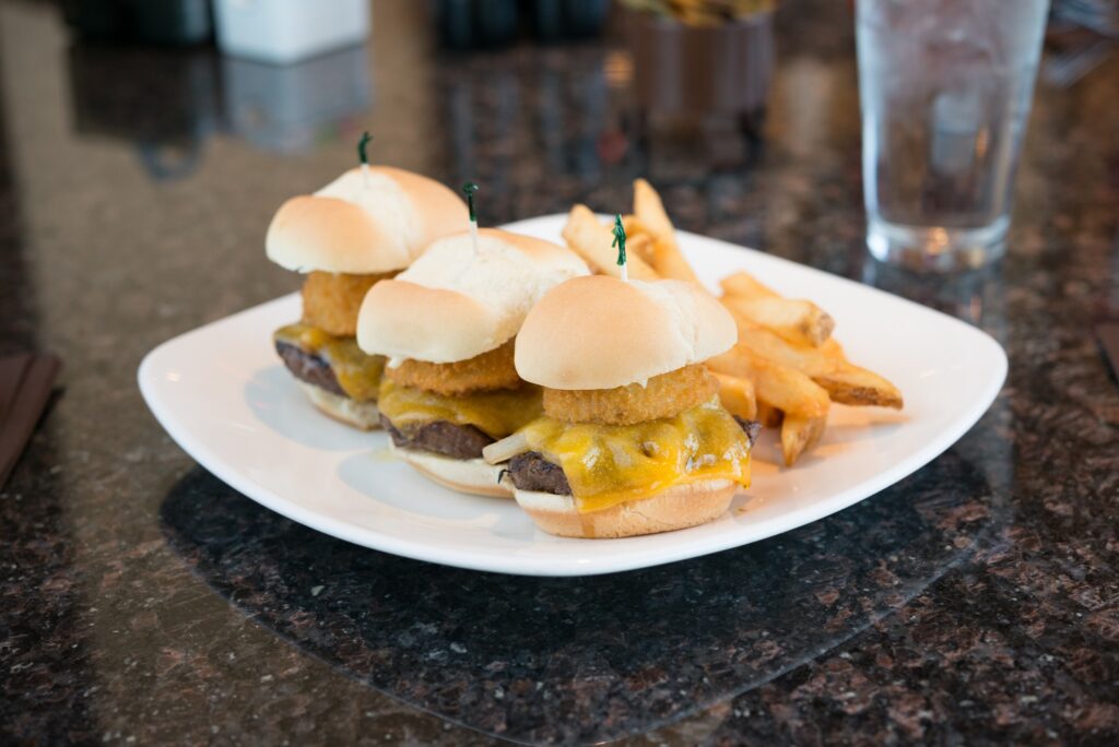 Three mini sliders lined up on a plate.