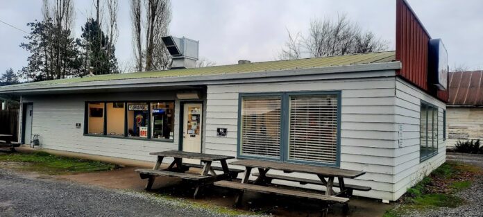 The outside of Tammy D's. It's an unassuming white building with two wooden picnic tables outside.
