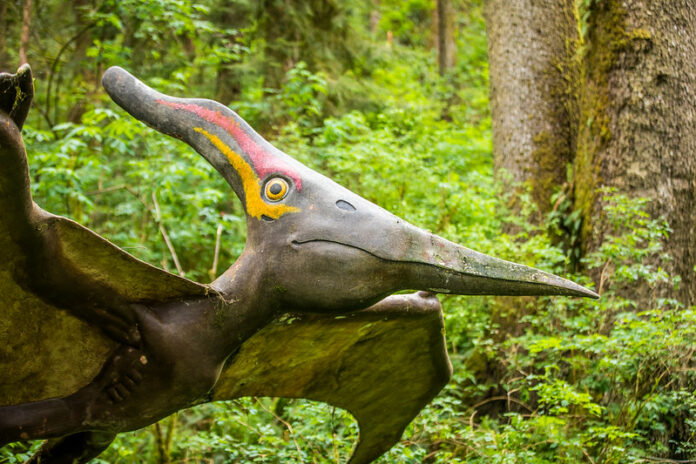 A sculpture of a flying dinosaur in the forest.