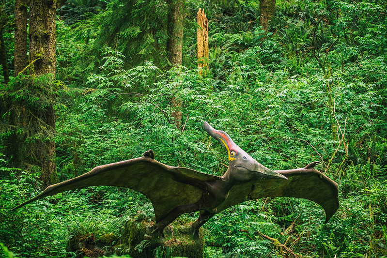 A sculpture of a flying dinosaur in the forest.