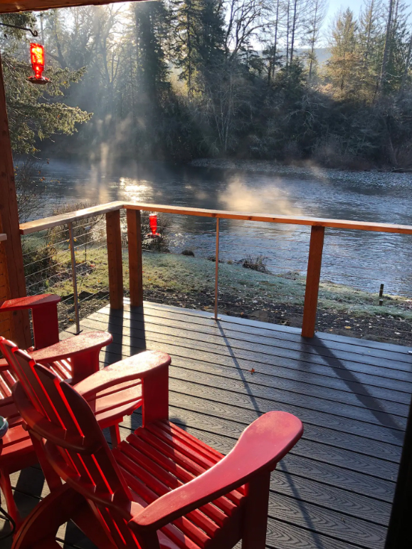 The private deck has two wooden chairs painted red and a view of the river.