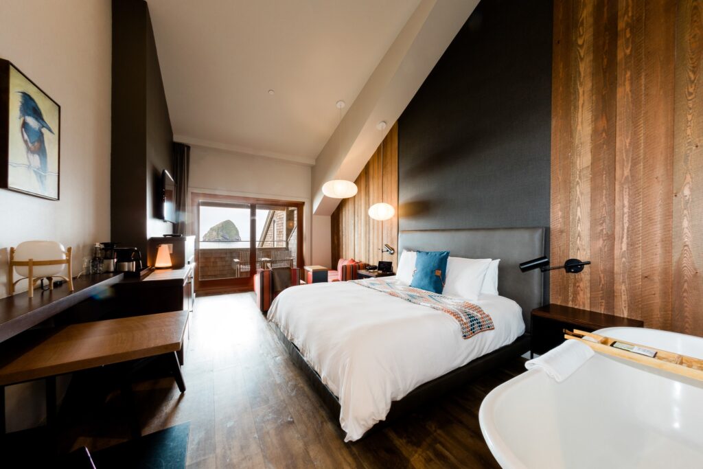 Two large white beds in a room with wood floors, wood accents on the walls, and black feature walls. The room is bright and airy looking.