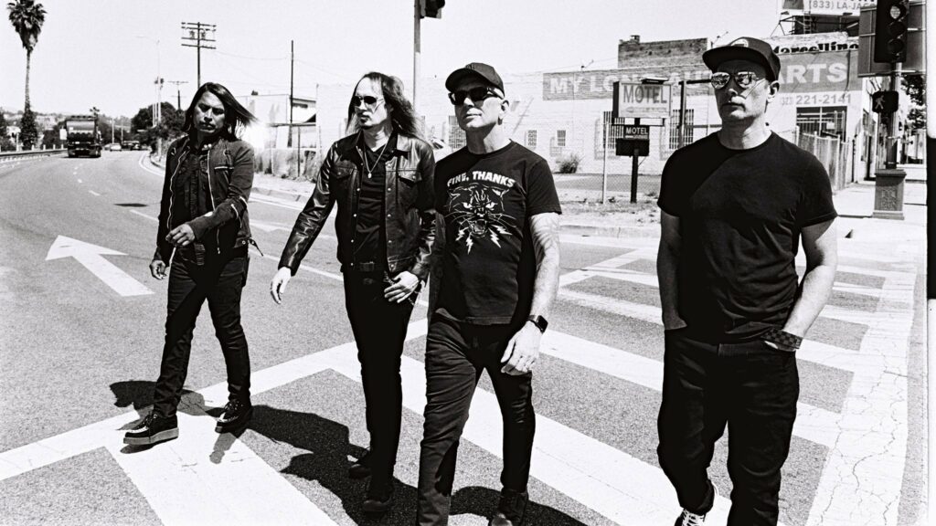 A black and white photo of the band members of Everclear crossing a street.