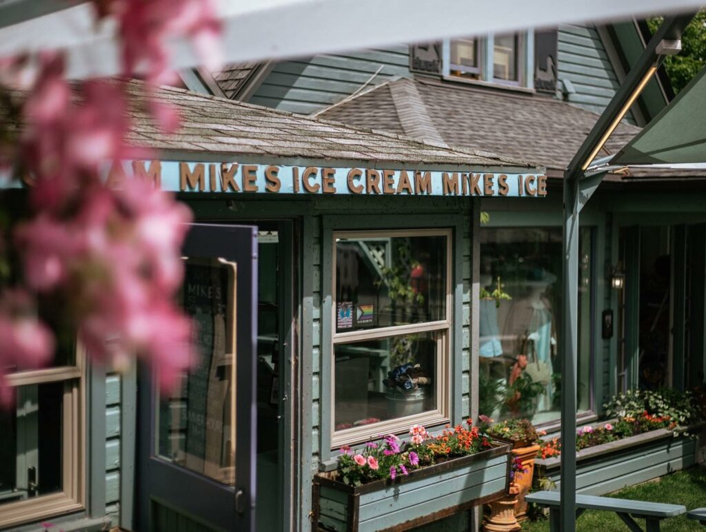 The outside of the cute Mike's Ice Cream shop. The building looks like a house and is a cute sage or aqua green color.