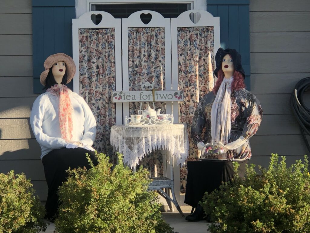 Two scarecrows on a porch.
