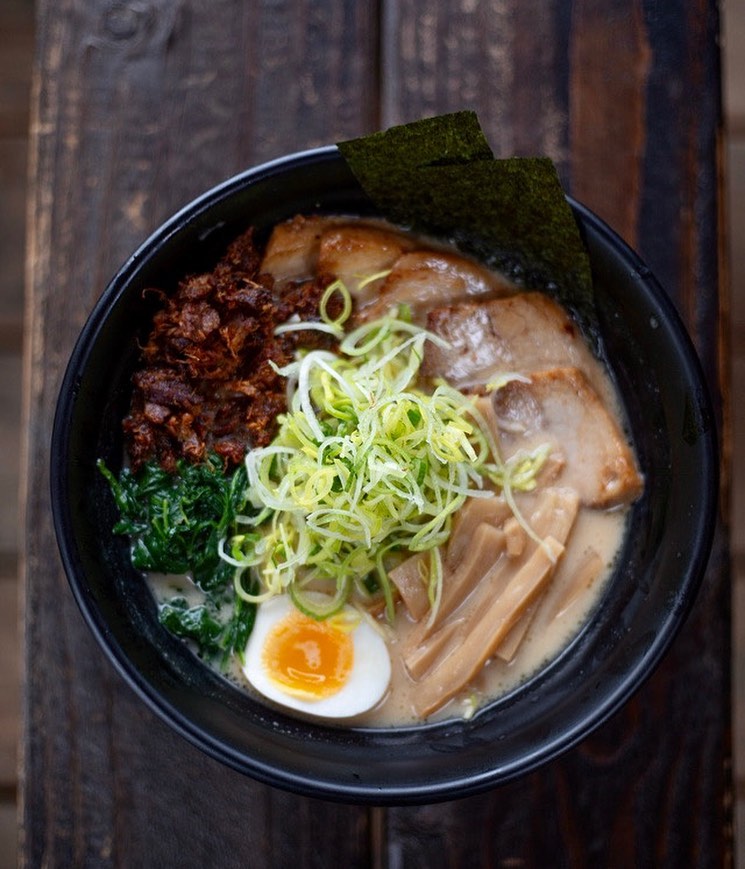 A yummy looking bowl of ramen with green vegetables and a boiled egg.