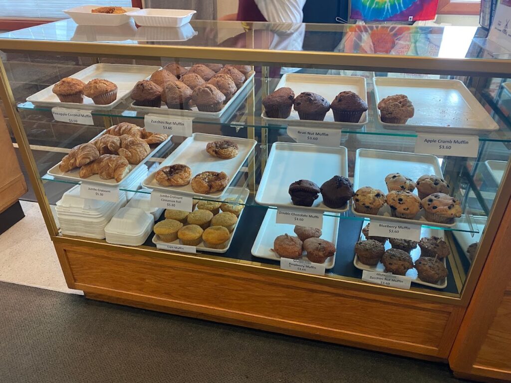 A glass display case full of fresh baked muffins of several varieties.