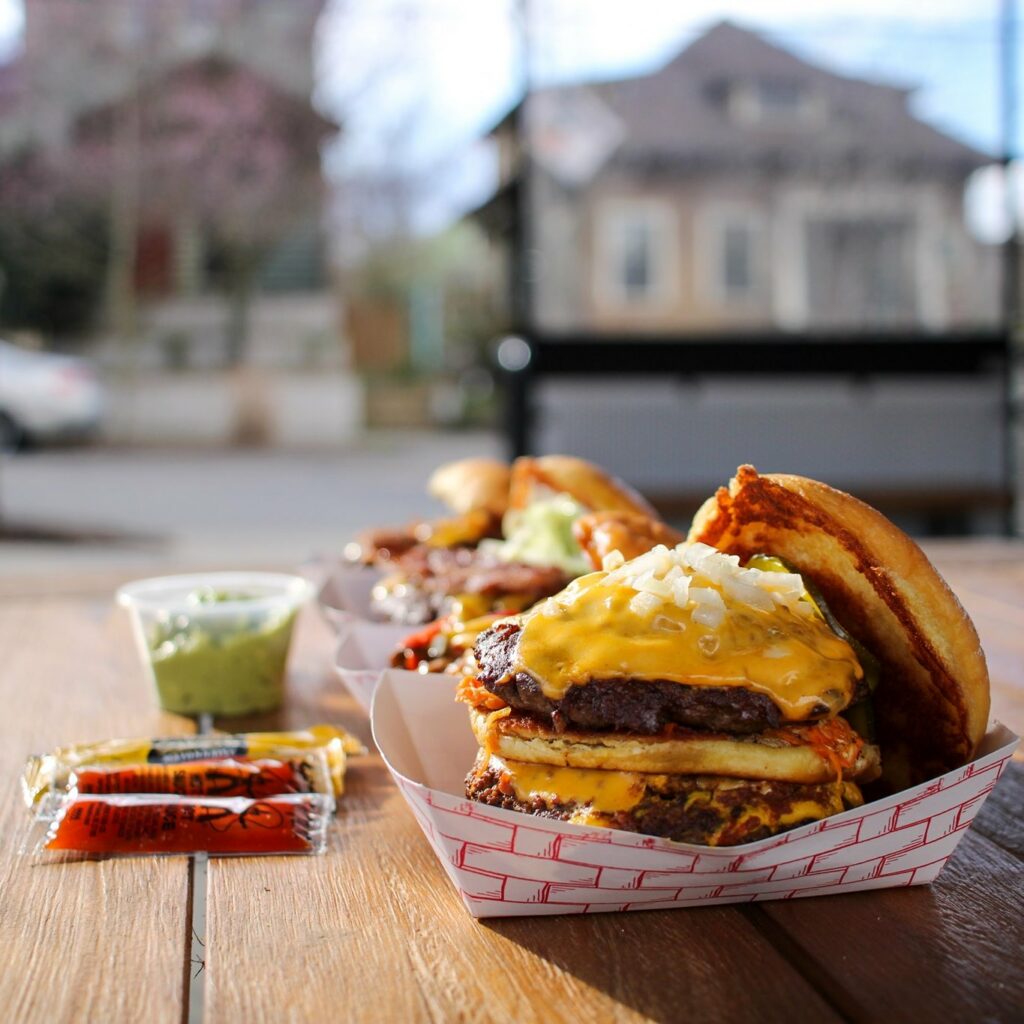 Two absolutely delicious looking burgers on a picnic table at Bless Your Heart Burger in Portland, Oregon.