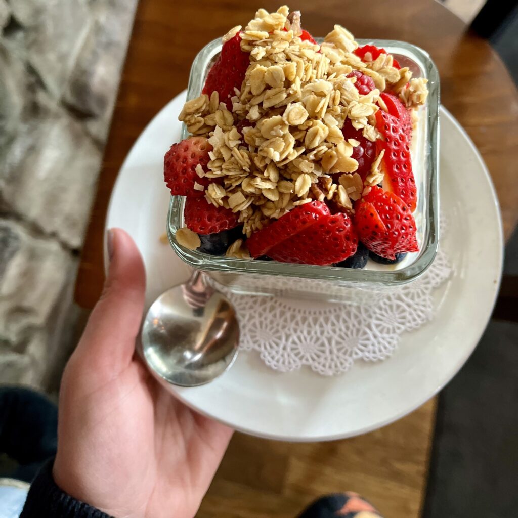 A colorful fruit parfait, toppedw ith bright red strawberries and oats.