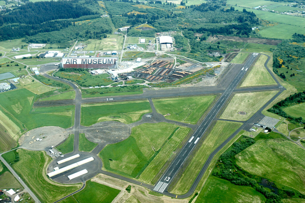 A colored aerial photo of the Tillamook Air Museum and the surrounding runways and green fields.  In the photo, a lumber yard is next door to the air hangar. tillamook air museum, planes, WWII, history, family things to do, oregon coast