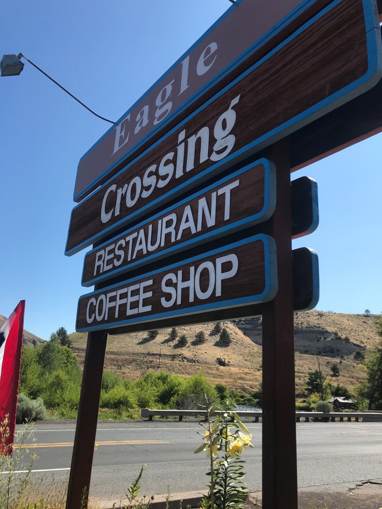 The brown sign outside of Eagle crossing restaurant. It has a blue border.