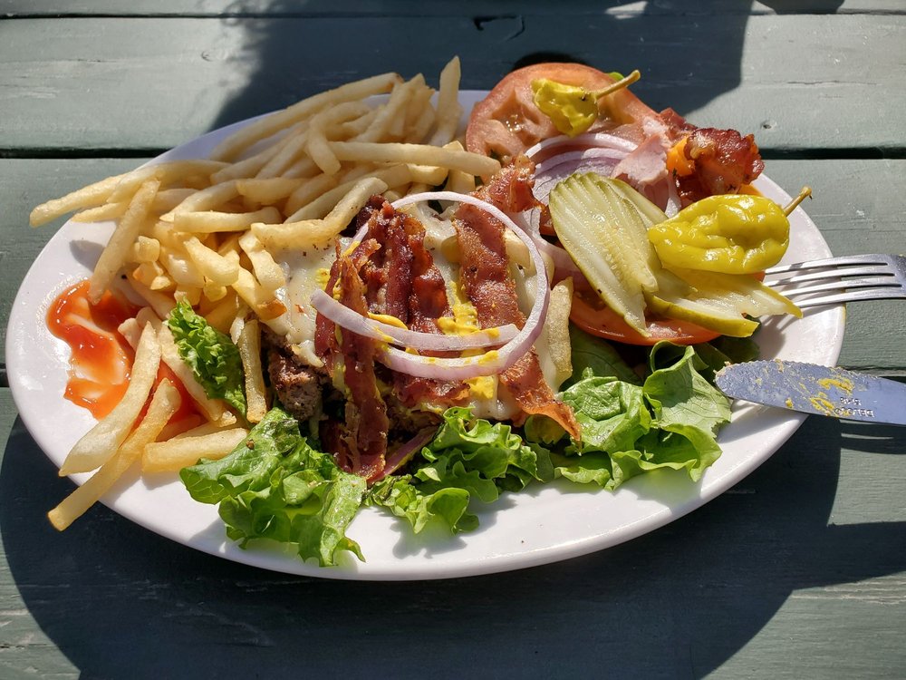 A Bacon cheeseburger with fries and a pepperoncini on the side.