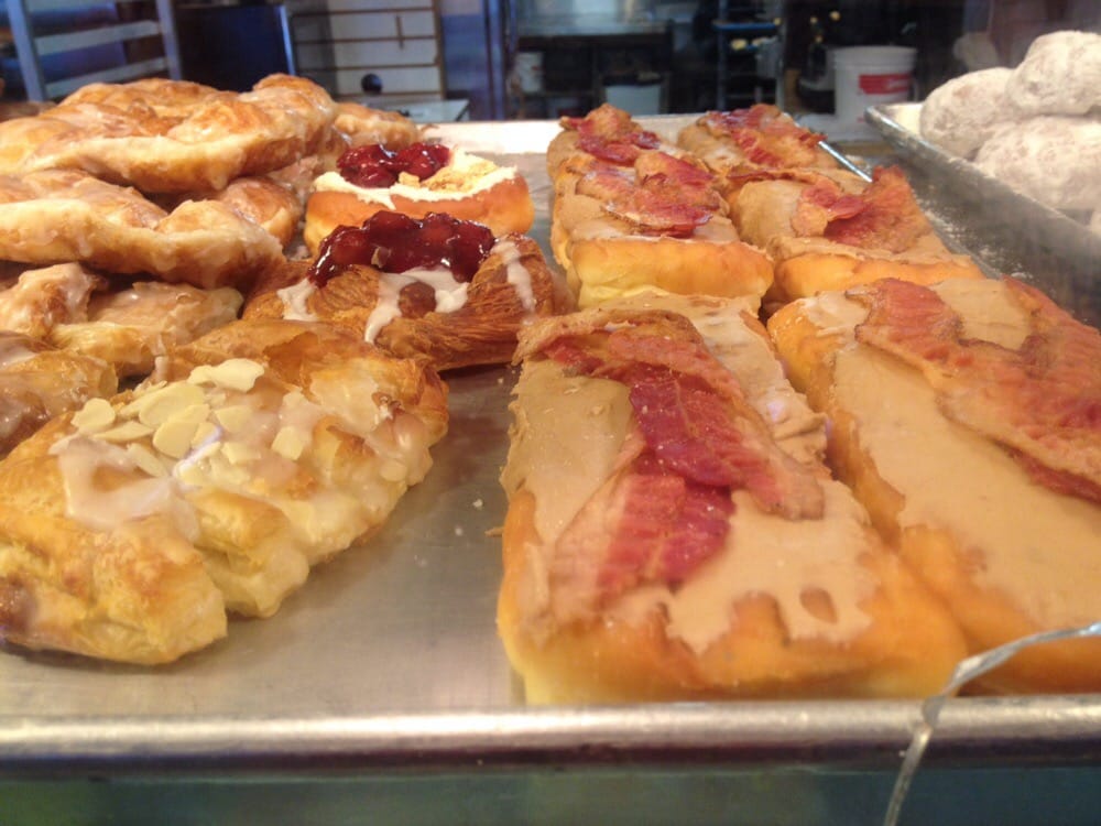 Maple bacon donuts as well as several other varieties in the glass case.