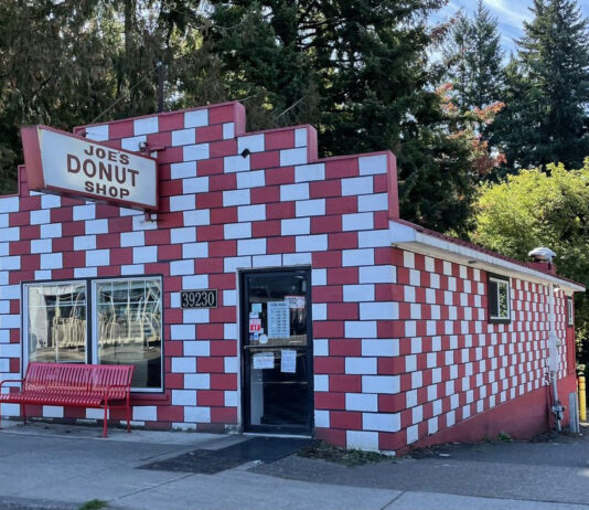 The exterior of Joe's Donuts in Sandy, Oregon. The building is red and white checkered bricks.