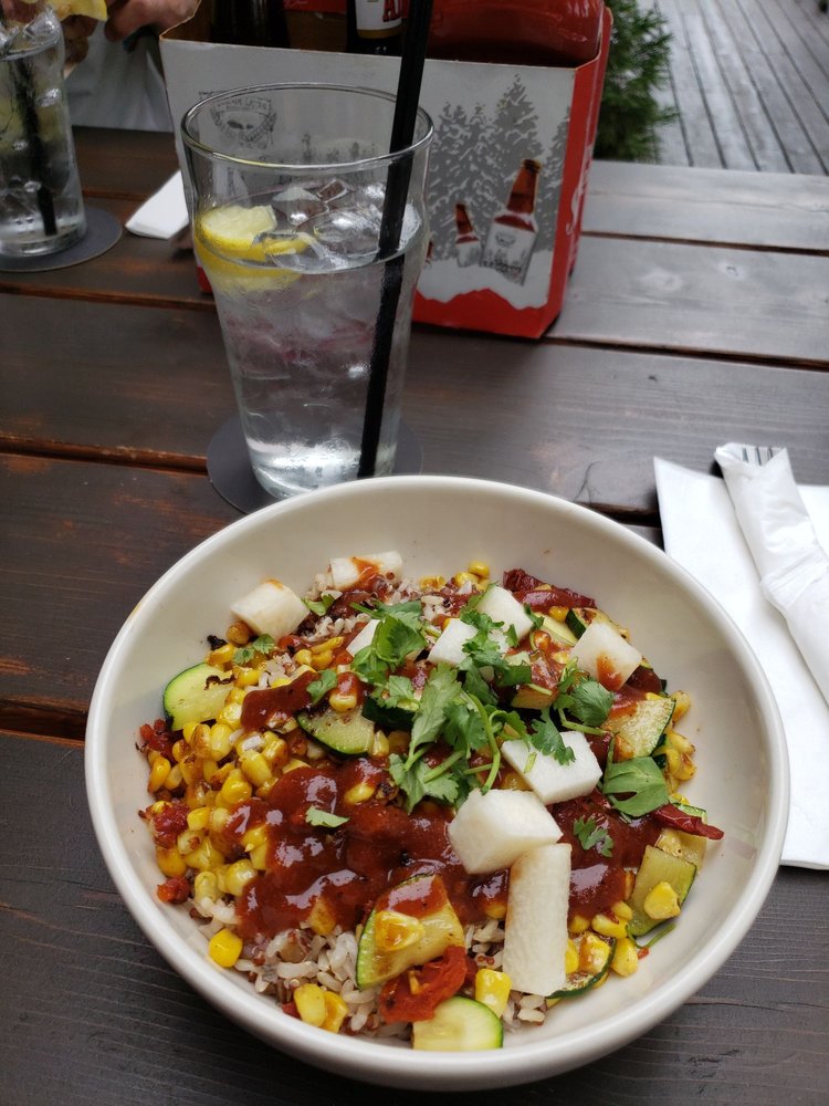 A plate of colorful vegetables and corn with a red sauce.