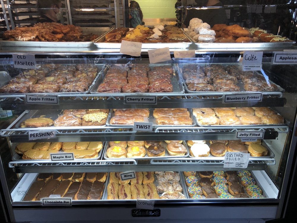 A glass case with over a dozen types of donuts.