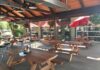 The covered outdoor seating area at Cascade Lakes Pub 7th Street in Redmond, Oregon. there are nice wooden picnic tables under a wooden roof.