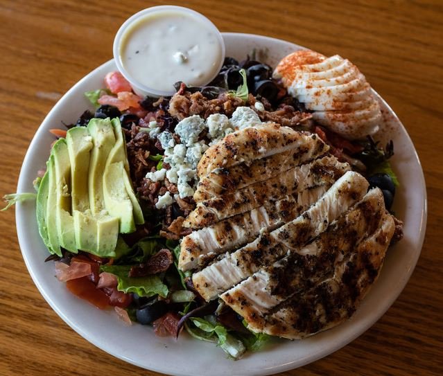 A tasty looking salad with avocado and chicken.