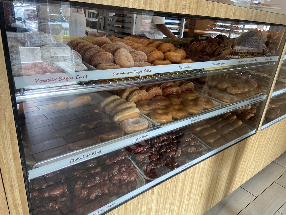 Over a dozen kinds of donuts on display in a glass display case.