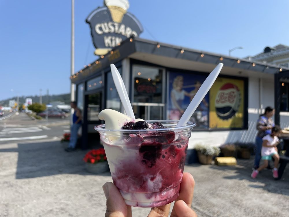 A delicious frozen custard with berries held up in front of the Custard King walk up stand.