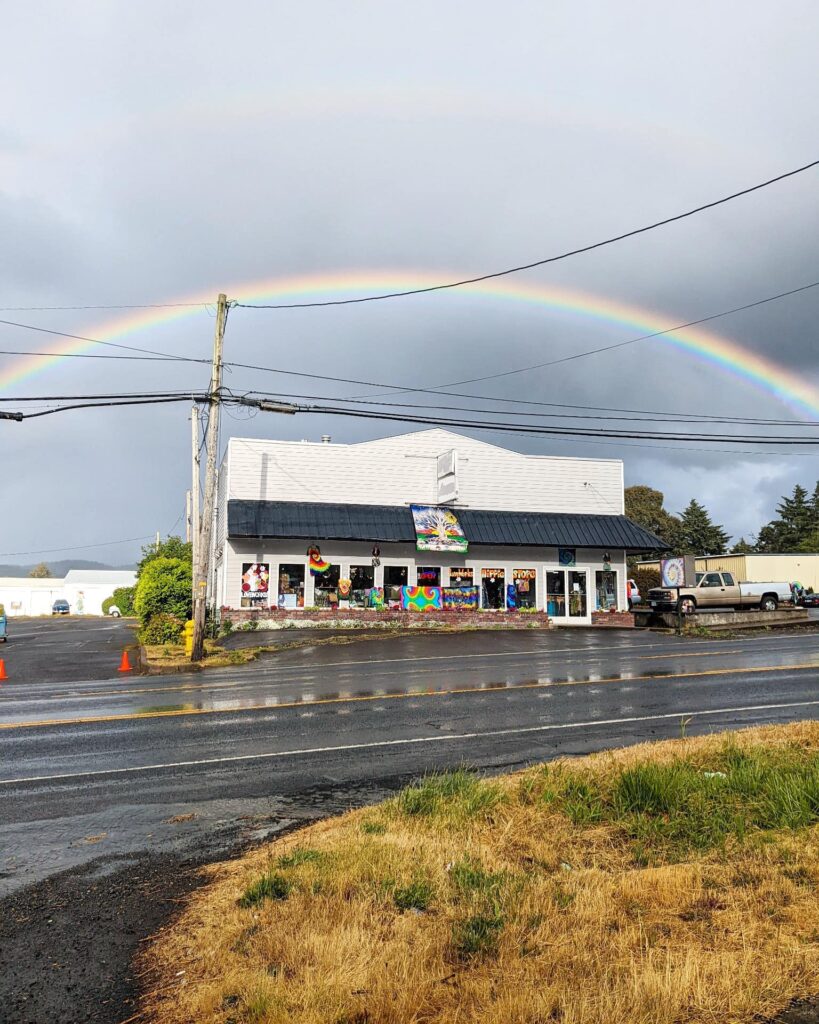 The outside of Love Works Hippie Store with a rainbow over it on a rainy day.