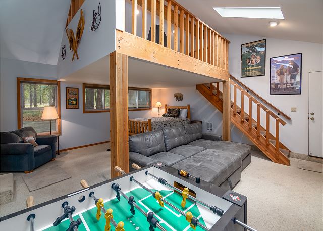 The interior of Duckpond #2.  There's a bed, a gray couch and foosball table as well as stairs leading up to another floor.