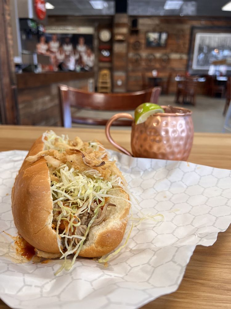 A hot sandwich piled high with toppings. There's a stylish copper cup in the background with a lime hanging over the edge.