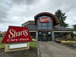 The outside of Sharis Restaurant. This one has a red sign with white lettering and accents of brown.