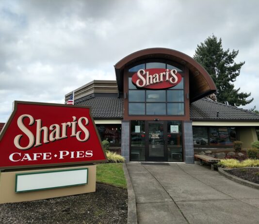 The outside of Sharis Restaurant. This one has a red sign with white lettering and accents of brown.