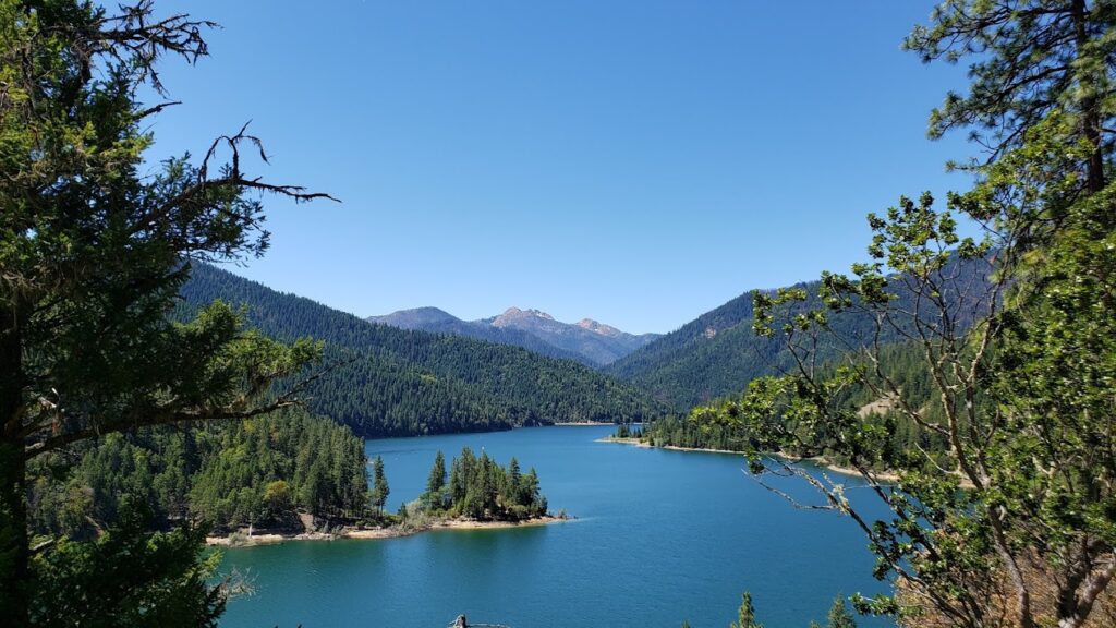 Applegate Lake surrounded by trees with mountains in the background.