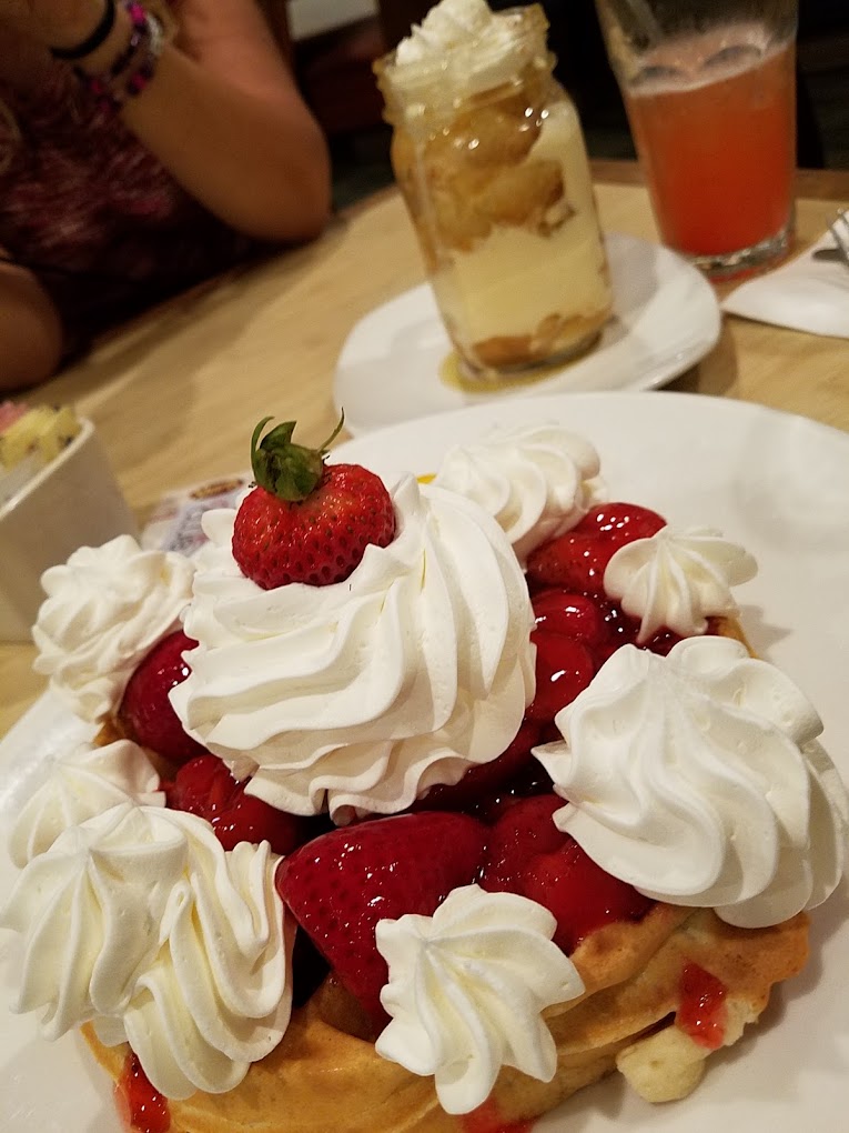 A waffle with strawberries and whip cream.