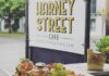A tasty looking plate of fresh food in front of the white and Black Harney Street Cafe sign.