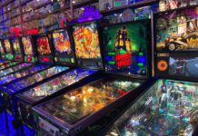 Several brightly lit pinball machines inside Next Level Pinball. The room is kind of dark, so the pinball machines are all lit up brightly. Looks like lots of fun!