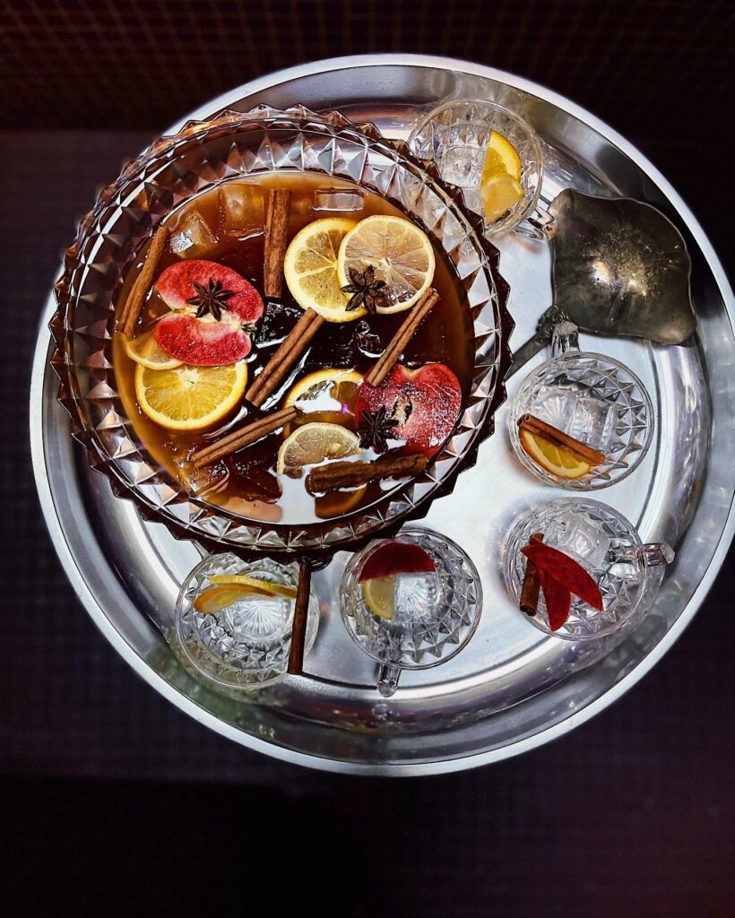 A colorful alcoholic drink with a variety of colorful fruit and cinnamon sticks in it.  It's in a large pitcher and is surrounded by glasses on a metal serving tray.
portland oregon, best restaurants, 2024, where to eat, best brunch, food and drink, bars, pizza, sushi, thai food, PDX, foodie heaven