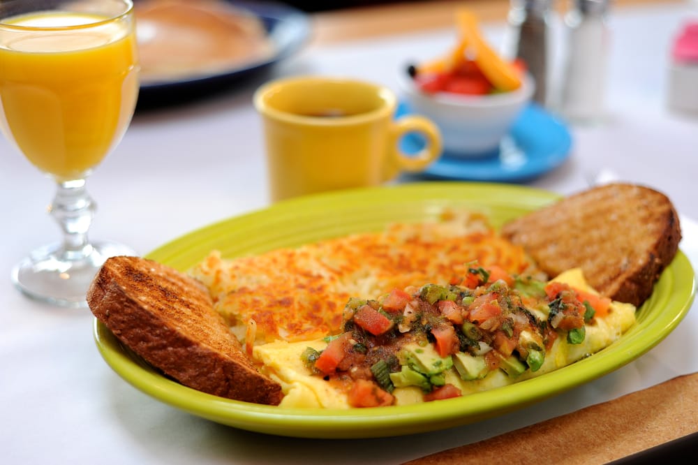 The Vera Cruz Omelet. It's on a red plate with a yellow cup and a blue plate in the background. The dishes the food is on are colorful and cute.