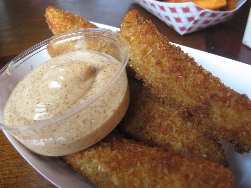 A basket of fried pickles with dipping sauce.