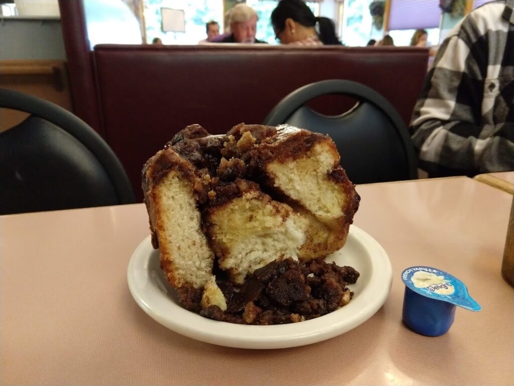 A giant cinnamon roll cut in half on a white plate.