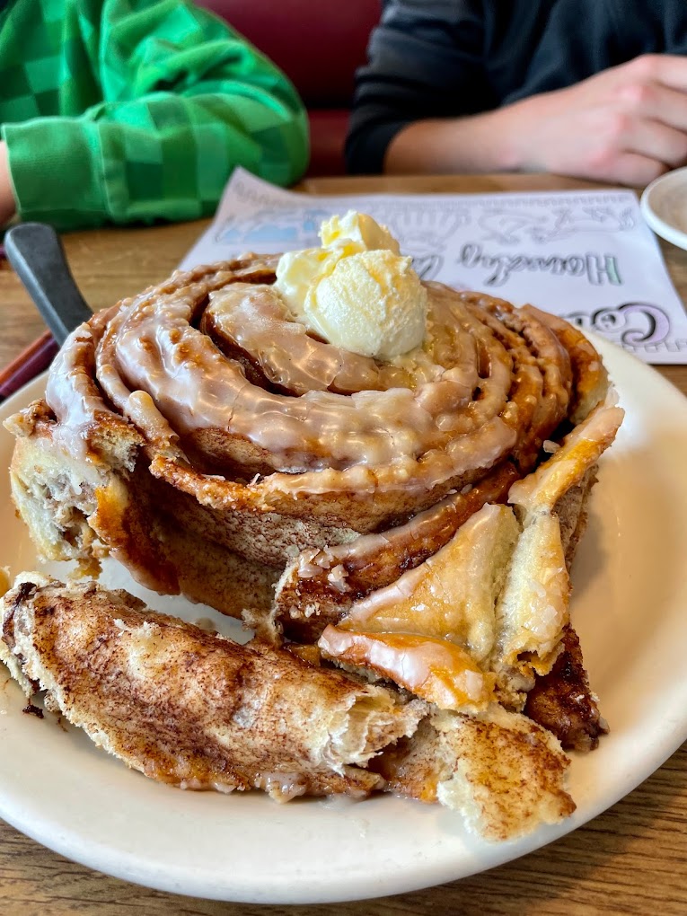 A large cinnamon roll with butter on top.