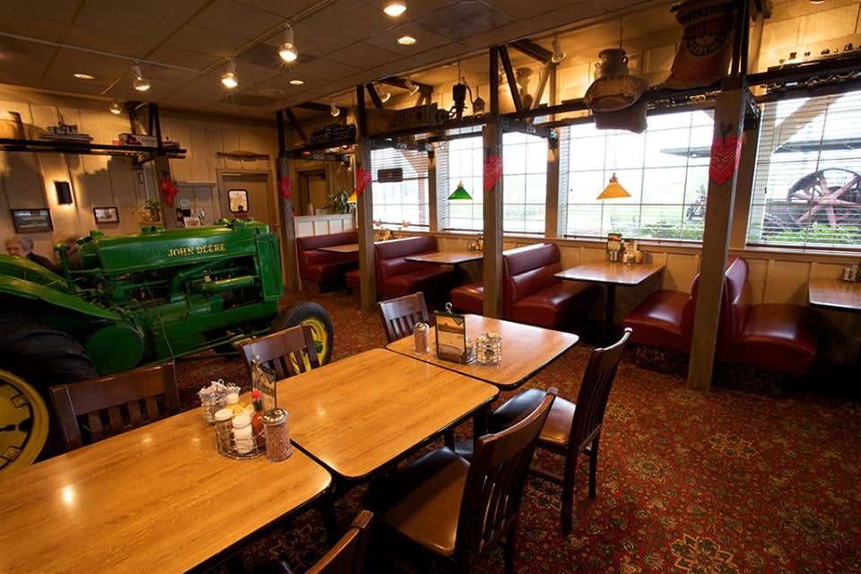 The inside of Cousins' Restaurant in The Dalles, Oregon. There's a green tractor inside next to the tables.