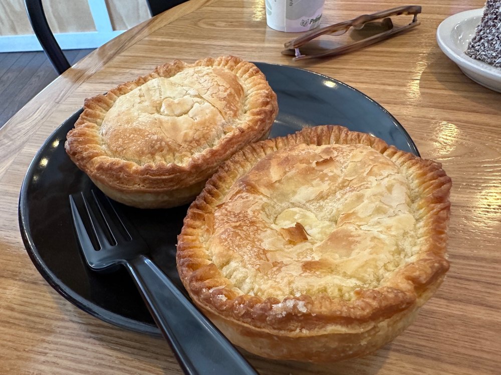Two meat pies on a black plate with a black fork.