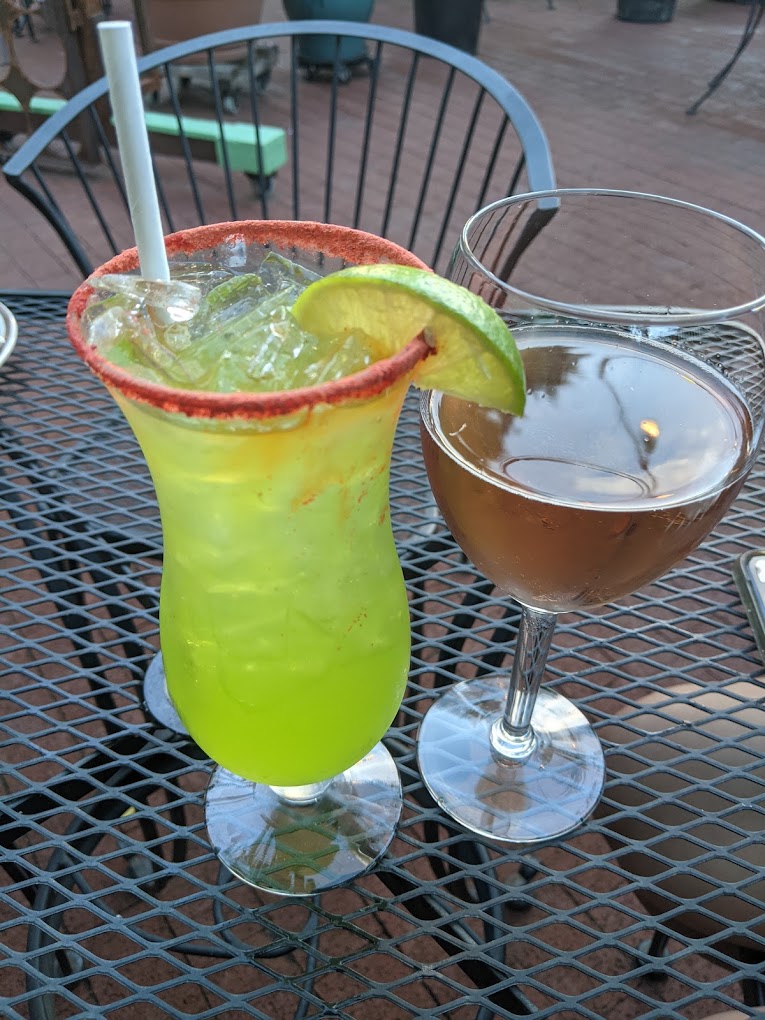 A colorful yellow cocktail with a lime. There is a second cocktail next to it.