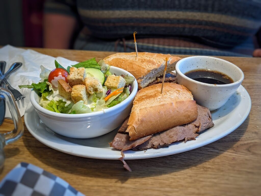 French Dip sandwich with a side salad and Au Jus dip.