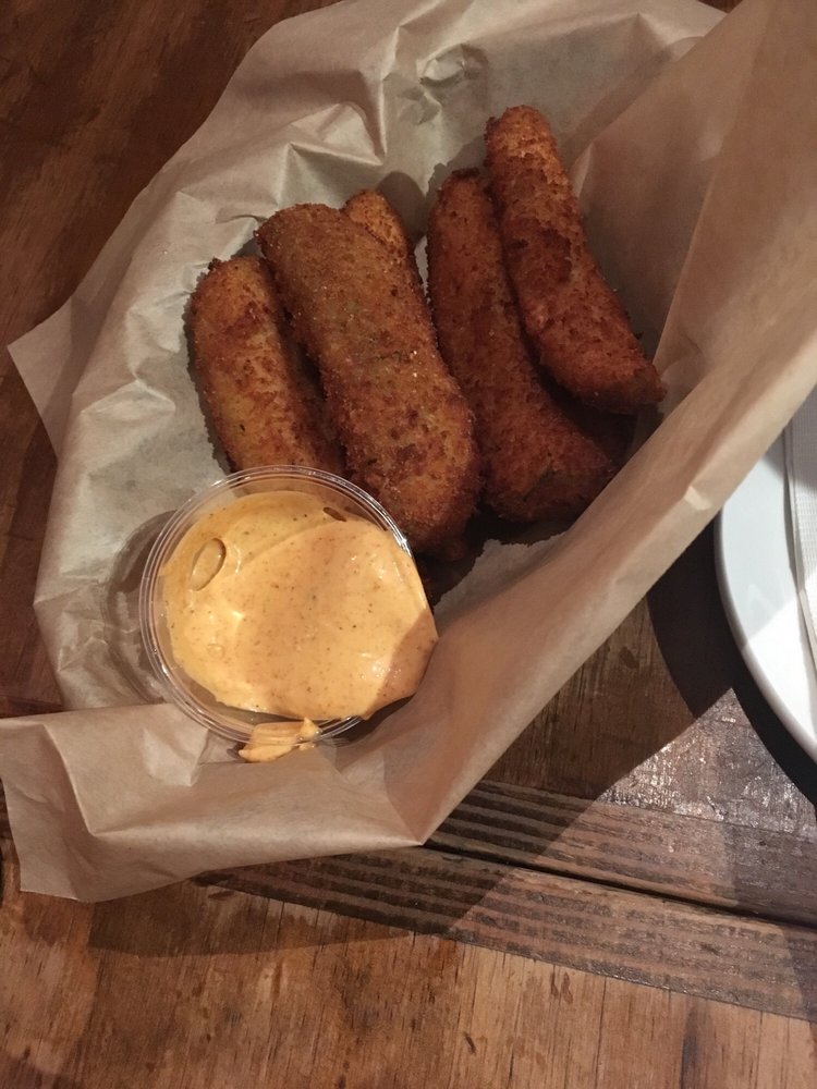 A basket of fried pickles with dipping sauce.
