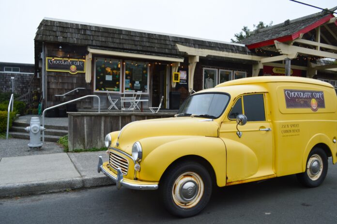 The outside of the Cannon Beach Café. There's an old vintage yellow delivery truck parked out front.