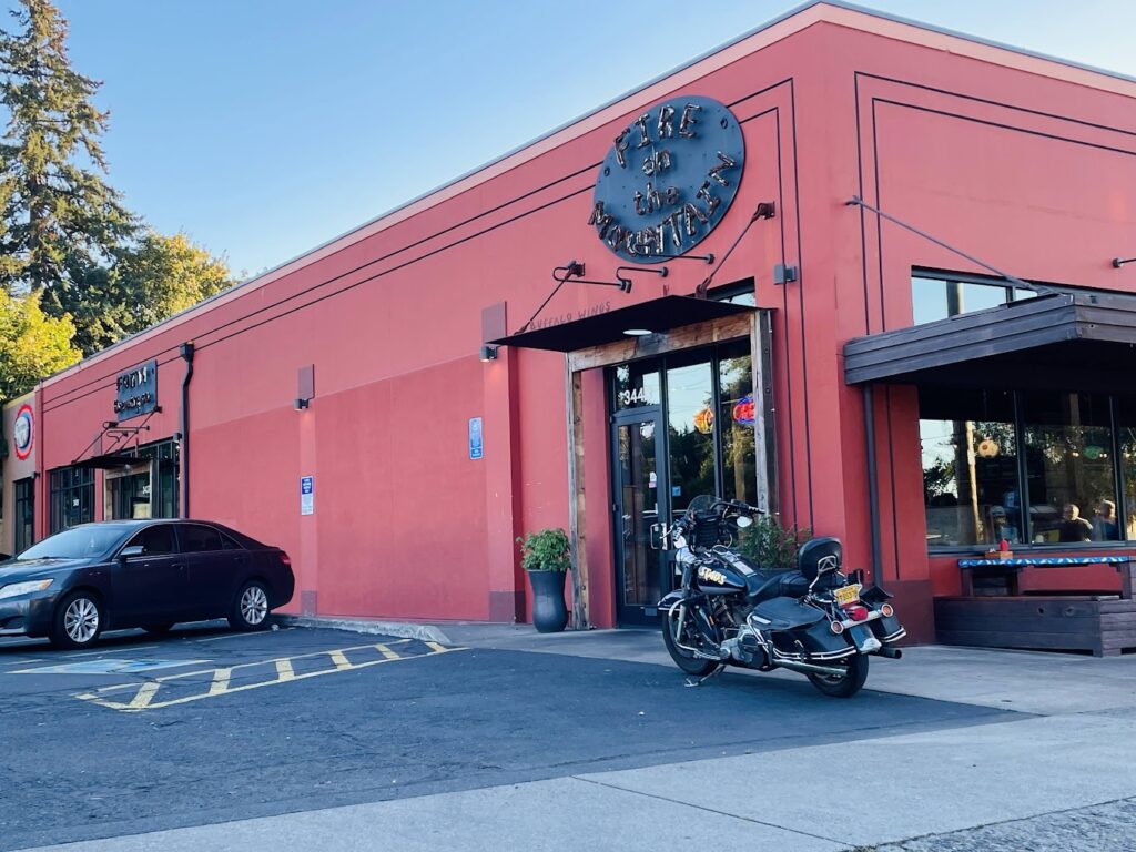 The outside of Fire On The Mountain. This location has a red building with a black sign.