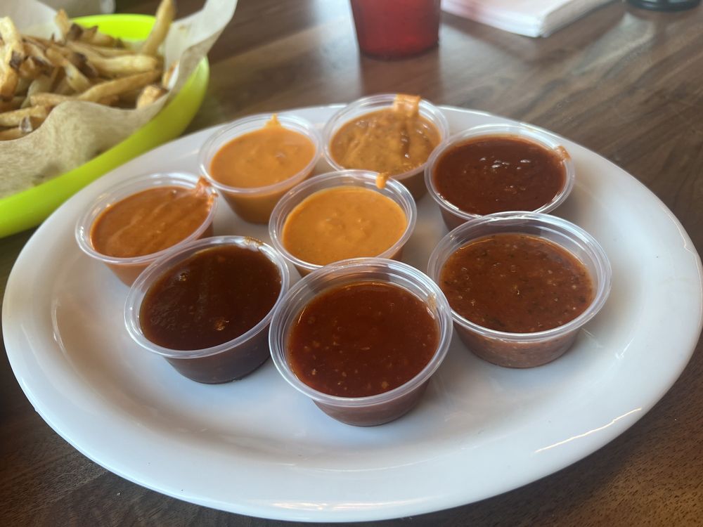 A plate full of containers of different types of dipping sauces.