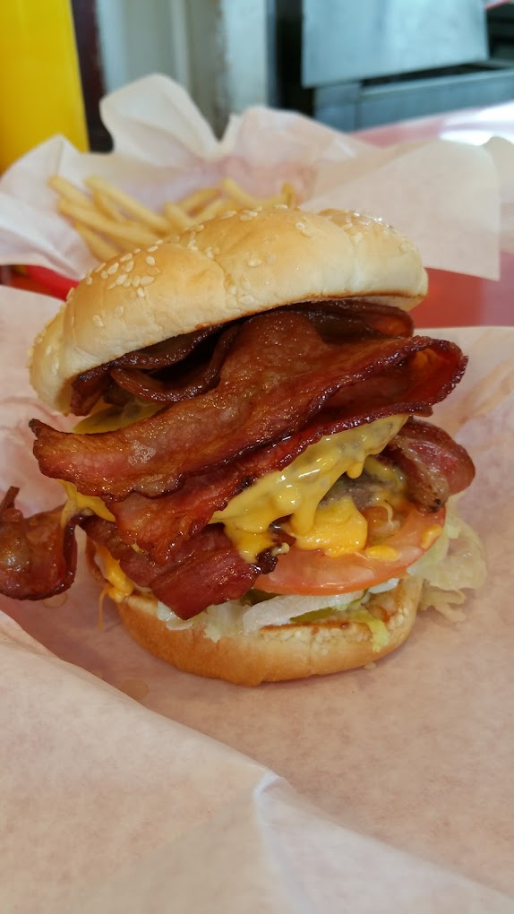 A bacon cheeseburger with extra bacon, tomato and lettuce.