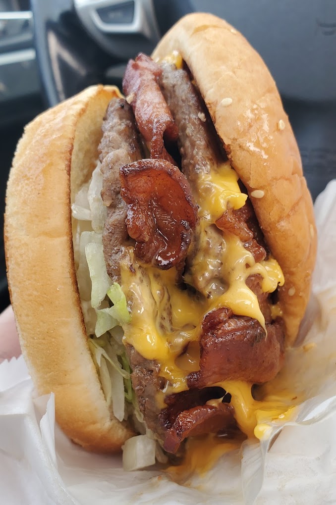 A bacon cheeseburger with lettuce.