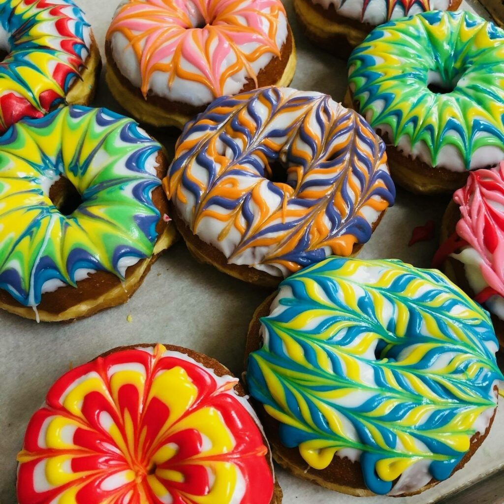 Donuts with colorful tie dye frosting patterns on top.