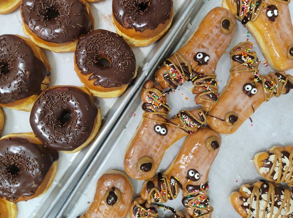 Round chocolate donuts with chocolate sprinkles, and a bunch of funny 'Deer In The Headlight' donuts.